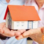 Twee ouders bieden hun kind symbolisch een huis aan als ondersteuning bij de aankoop via een familiehypotheek.