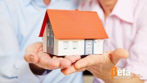 Twee ouders bieden hun kind symbolisch een huis aan als ondersteuning bij de aankoop via een familiehypotheek.