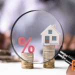 Illustratie van een vergrootglas met daarin een procentteken en een huis, symboliserend de hypotheekrente en woningfinanciering in 2025.