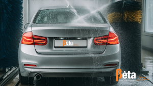 Zilverkleurige auto wordt gewassen in een automatische wasstraat met waterstralen en borstels – illustratie bij schade en verzekeringstips van Bèta Financiële Diensten